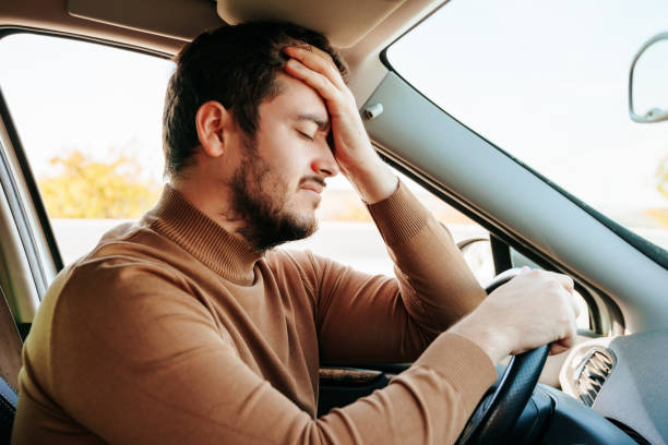 un jeune conducteur, les yeux fermés, est assis dans sa voiture et se repose. - overworked worried distraught front view photos et images de collection