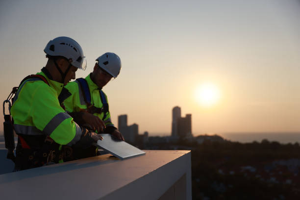 Solar energy engineers collaborate on a rooftop, discussing and designing as the sun sets.