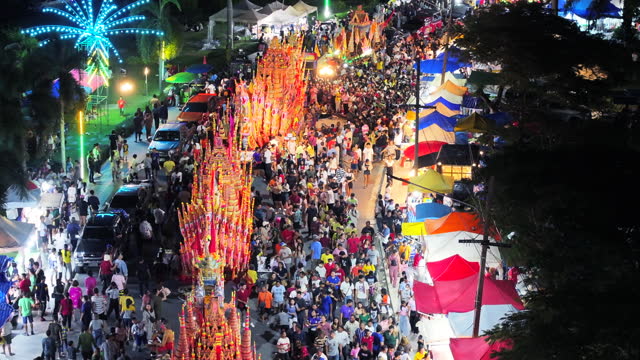 Aerial Drone Event the cultural heritage of the boat race parade festival. People give alms to a Buddhist monk with decorated boat parade along the road, Songkhla, Thailand
