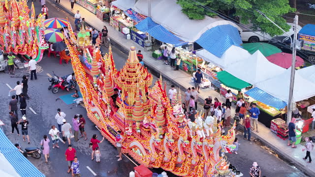 Aerial Drone Event the cultural heritage of the boat race parade festival. People give alms to a Buddhist monk with decorated boat parade along the road, Songkhla, Thailand