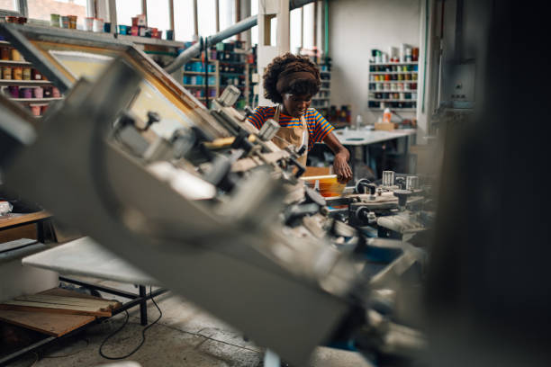 istock Interracial graphic technician silk screen printing on printing press 2147648527