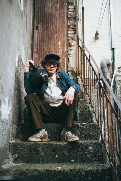 portrait of a teenager listening to music on headphones and sitting on the stairs