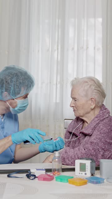 doctor teaching an elderly patient how to use a medical emergency call device.vertical video.
