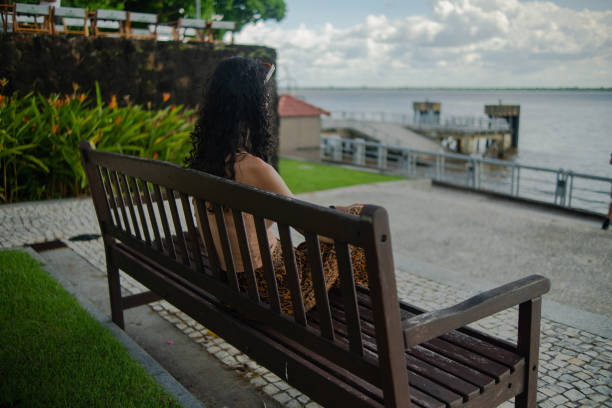 WOMAN ON A BENCH WATCHING THE GUAMÁ RIVER IN BELÉM DO PARA IN THE MONTH OF JUNE, THE THIRTEENTH OF TWO THOUSAND AND TWENTY-THREE