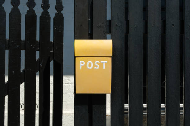 Yellow metal mailbox on a fence with an open gate..
