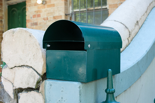 Blue mail box against a brick wall with a blue trellis.