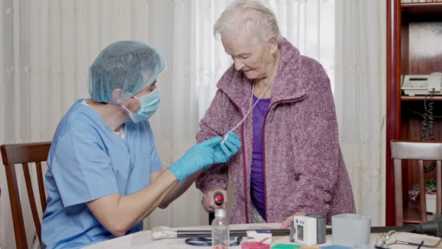 doctor teaching an elderly patient how to use a medical emergency call device