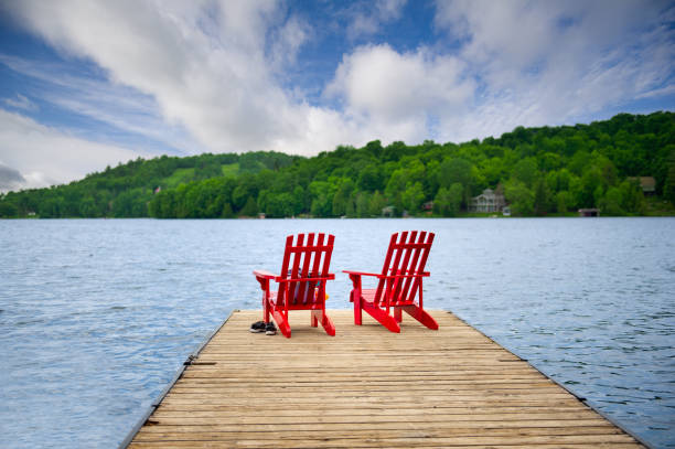 istock Two red Muskoka chairs rest on a wooden dock 2147663061