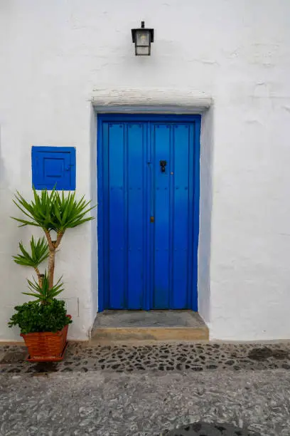 Charming bright blue door and potted palm in white village of Frigiliana Spain
