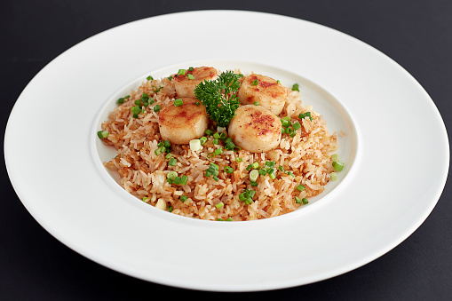 Garlic Fried Rice with Scallop served on white plate isolated on black background.