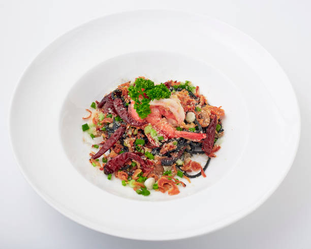 istock Black pasta stir fried chilli with shrimp topped with parsley, dried chilli, sliced spring onion, fried garlic, and cheese. Black spaghetti made from the ink in the squid. 2147665245