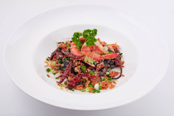 istock Black pasta stir fried chilli with shrimp topped with parsley, dried chilli, sliced spring onion, fried garlic, and cheese. Black spaghetti made from the ink in the squid. 2147665263