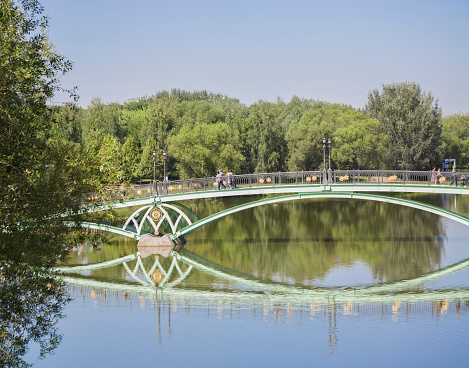 A metallic green bridge over the pond in the park of the Tsaritsyno Estate Museum. Moscow 08.17.2023