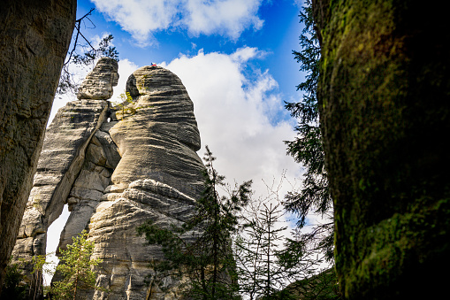 A towering rock formation stands prominently amidst the lush greenery of the Adrpach Teplice forest in the Czech Republic. The large rock formation dominates the landscape, showcasing the powerful forces of nature at work.