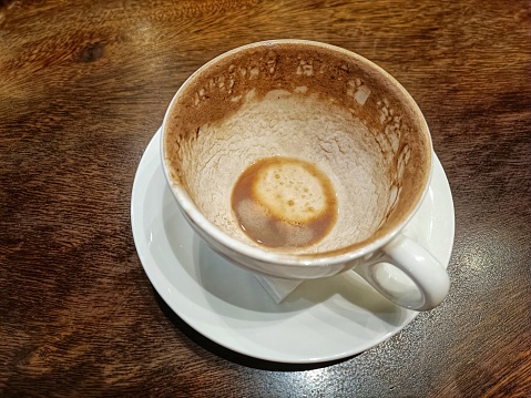 view of an empty coffee cup with brown residue on the side on the table