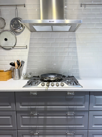 Modern kitchen detail with cabinets and stainless stove top and range hood