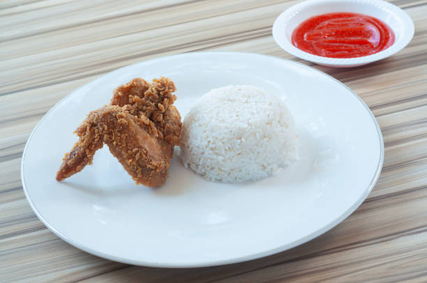 Fried Chicken with white rice and Vegetables as garnish. served in white plate