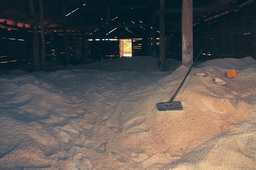 Mounds of harvested salt inside a spacious, dimly lit wooden and run down storage house, a traditional local product from Kampot Cambodia