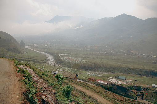 A misty view of Lao Cai Village in a valley with a river flowing through, surrounded by mountains. Sa pa, Vietnam