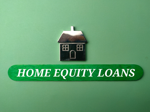 Toy house with text HOME EQUITY LOANS on green background.