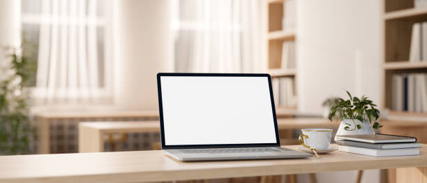istock A white-screen laptop computer on a wooden table in a beautiful minimalist library or bookstore. 2147669646