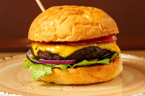 Cheeseburger is beef patty, melted cheese, fresh lettuce, and ripe tomato are clearly visible.