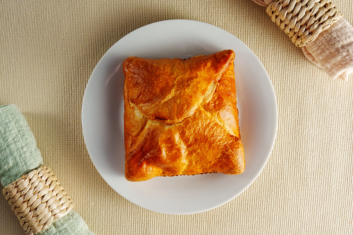 Delicate Delights: A Flaky Puff Pastry Placed Elegantly on a Gleaming White Plate