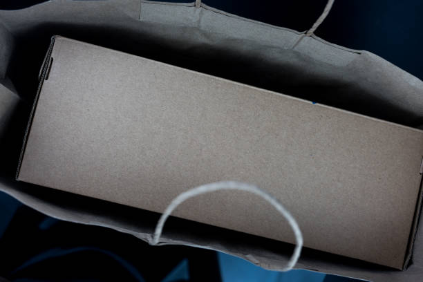 Realistic cardboard box or parcel box mockup in brown shopping bag. Top view