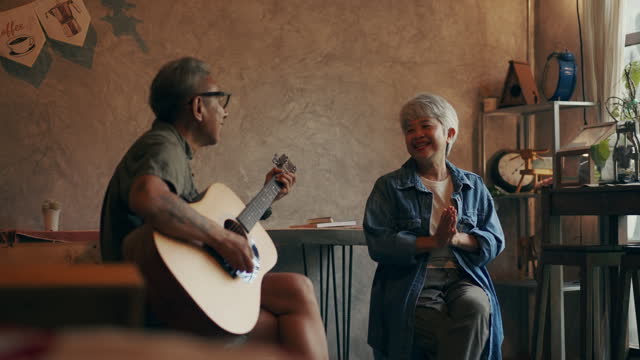 Senior couple playing guitar and singing together having fun.