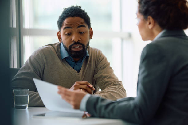 istock Black man and his insurance agent analyzing paperwork during a meeting in the office. 2147673138