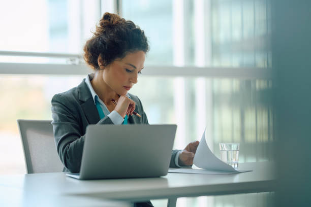 istock Corporate manager going through paperwork while working on laptop in the office. 2147673156