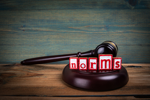 NORMS. Red alphabet letters and judge's gavel on wooden background. Laws and justice concept.