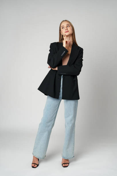 istock Young Woman Wearing Black Jacket and Jeans posing on gray background studio shot . 2147677954
