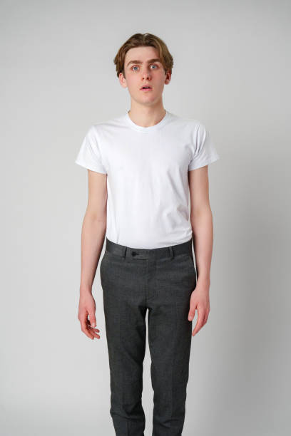 istock Young Man Standing in a Plain White T-Shirt Against a Gray Background 2147677986