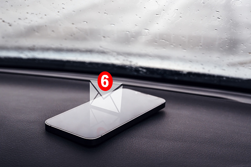 Text message notification icon on smartphone in car, selective focus