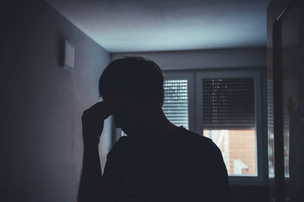istock Silhouette of depressed sad man in dark room with window shutters pulled down 2147678388
