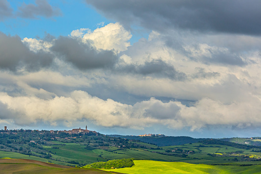 The Val d'Orcia in Tuscany, Italy, is a breathtaking expanse of rolling hills and lush fields. In the distance, the small town of Pienza adds a charming touch to the picturesque landscape, with its terracotta rooftops standing out against the greenery. It's a scene that epitomizes the timeless beauty of rural Tuscany.
