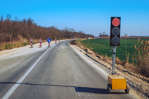 Traffic light signalization during road maintenance, red stoplight for traffic regulation, selective focus
