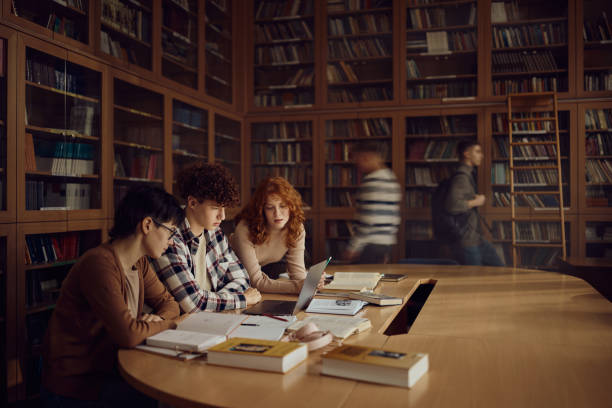 istock Group of high school students using laptop in library. 2147679505