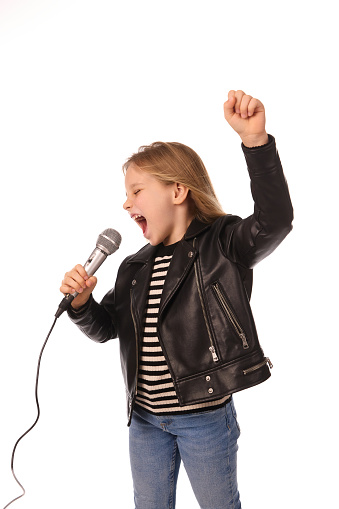Happy little girl in smart clothes singing a song with a microphone