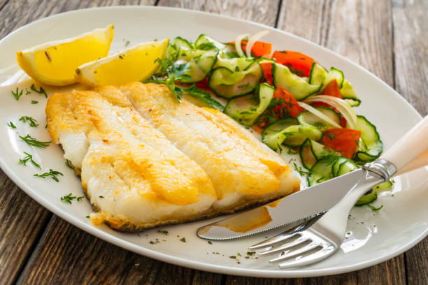 istock Fried halibut fillet and fresh vegetables on wooden table 2147679982