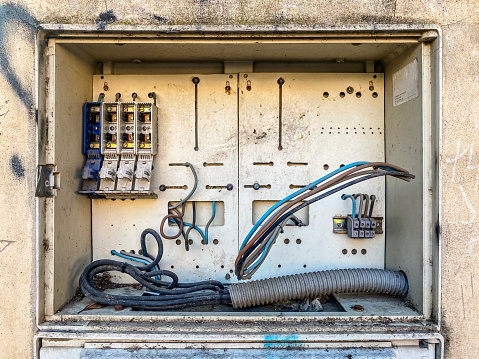 Close-up front view of empty electrical panel outdoors in the street with only some cables left in it