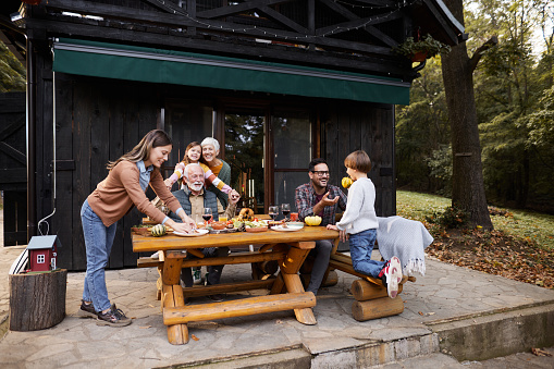 Happy multi-generation family enjoying during an autumn meal on a patio. Copy space.