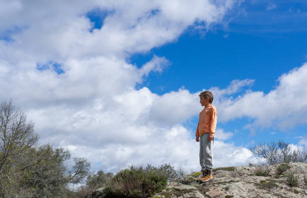 istock Boy standing on a rock in nature looking at the horizon 2147682930