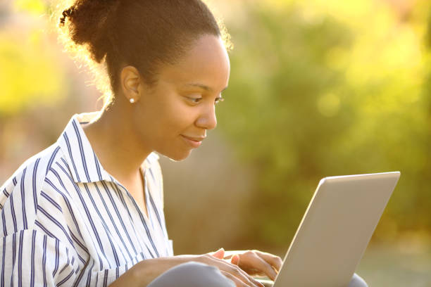 istock Black woman in a garden using laptop 2147683016