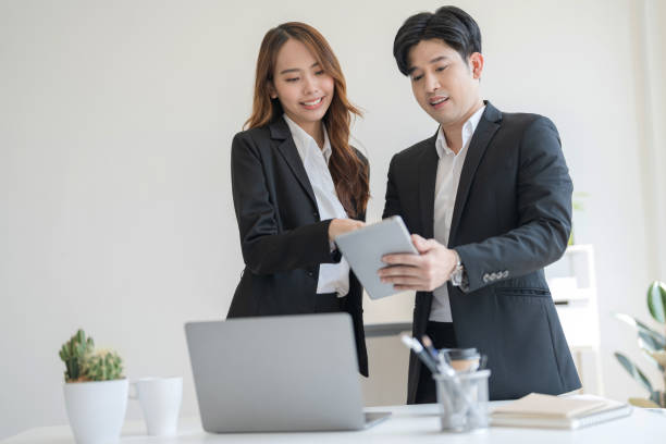 istock Business people stand together at a desk talking on their laptops 2147683434