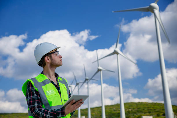 istock Young engineer man looking and checking wind turbines at field 2147683564