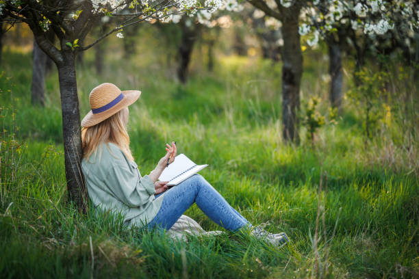 istock Woman writes her diary and resting in blossoming orchard 2147684639