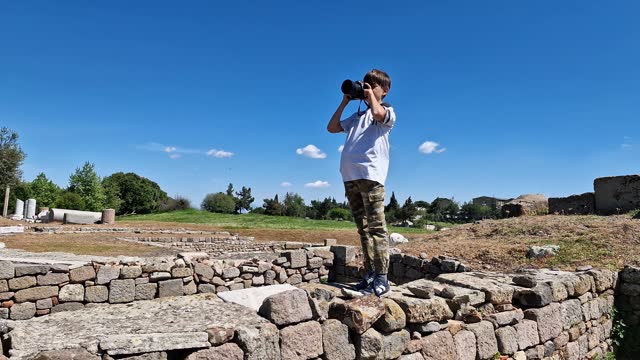 Little boy taking photos and videos with a professional camera in the ancient city