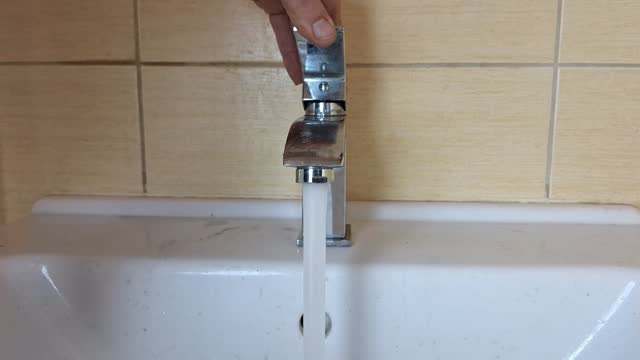 A plumber tightens a faucet aereator to a tap. The plumber's hands tighten the tap aeretor to the faucet. Concept of small repairs in household, DIY, crafts, construction.